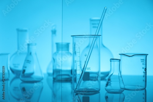 Foto Laboratory glassware on mirror surface against light blue background