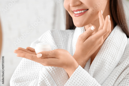 Young woman applying cream ...