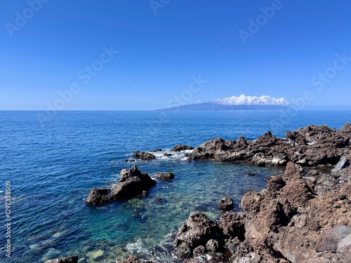 Schilderij op canvas Seascape with La Gamora on the horizon, blue sea and sky and rocks