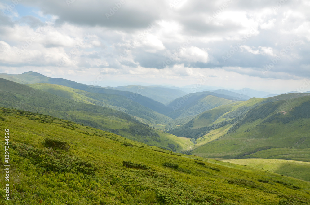 Fototapeta premium Captivating view showcasing lush green valley, surrounded by mesmerizing mountain ridges under dramatic cloudy sky, conveying sense of peace, nature's beauty, and scenic tranquility. Carpathians