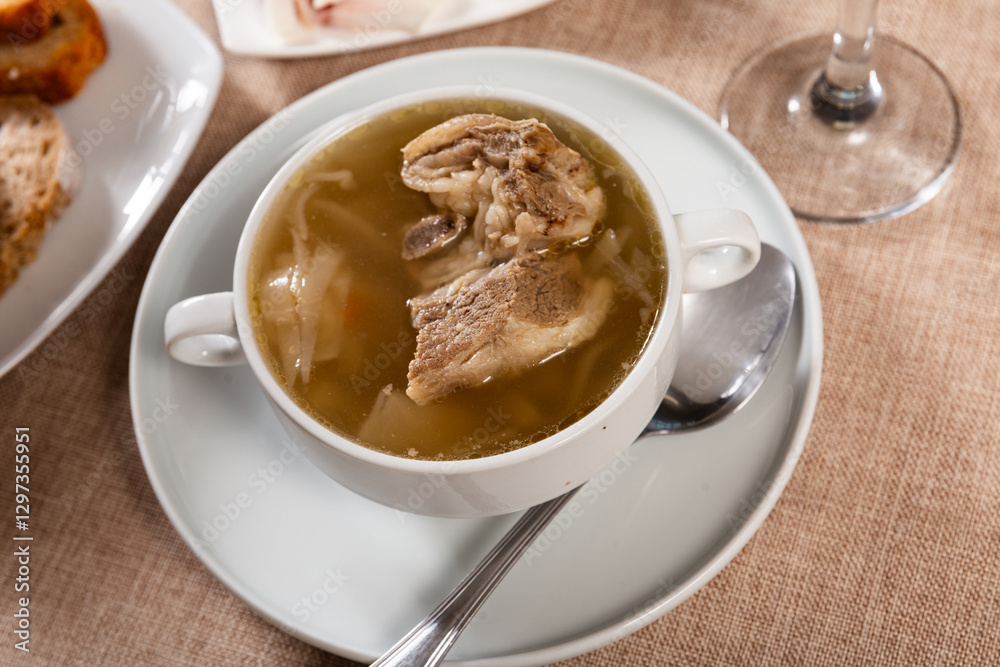 Freshly prepared hearty lunch awaits on table - fragrant cabbage soup with potato, carrot and pork rib. Dish is complemented with plate of bacon and bread. Freshly prepared hearty lunch awaits on table - fragrant cabbage soup with potato, carrot and pork rib. Dish is complemented with plate of bacon and bread.