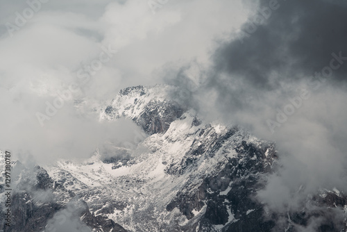 Snow-covered Dolomite peaks shrouded in dramatic clouds, creating a mystical and majestic alpine atmosphere.