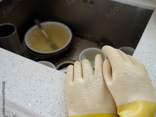  Dirty Dishes in Sink with Cleaning Gloves. Household Chores Concept