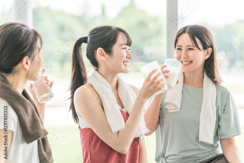 Bild auf Leinwand スポーツジムのヨガ教室で休憩をしながらプロテインや水を飲むする女性達