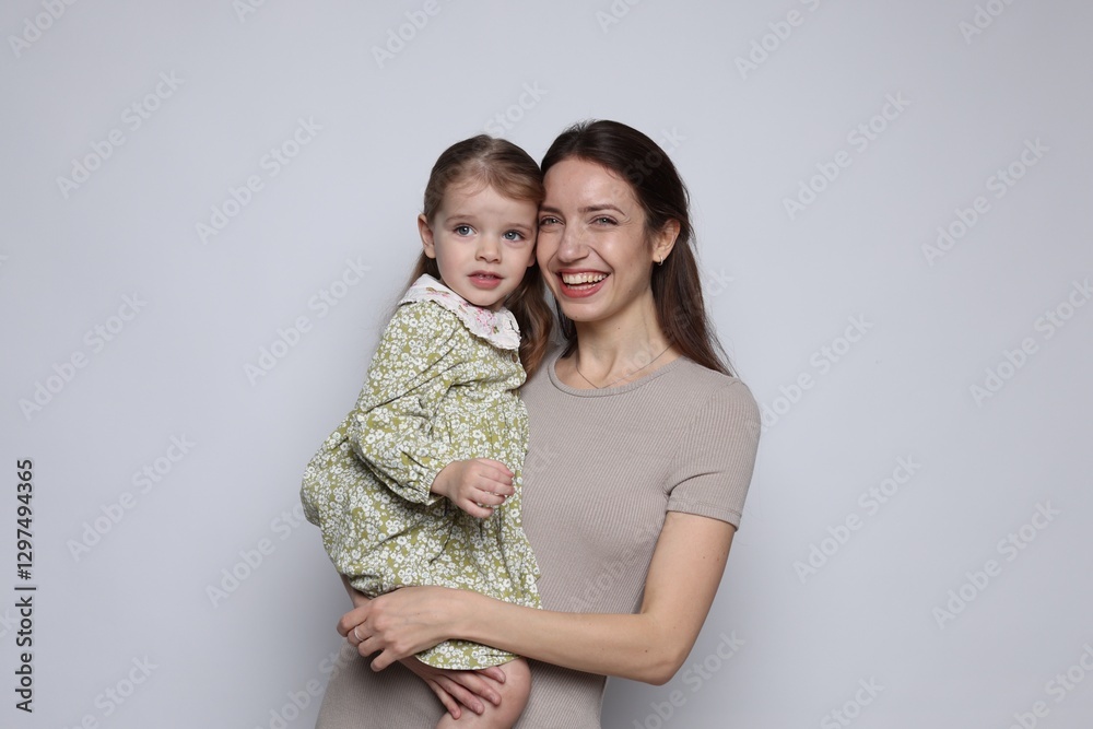 Naklejka premium Portrait of happy mother with her cute little daughter on grey background