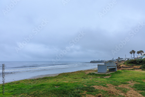 Elevated vista point with a stone bench on top of green grassy lawn above the coast of North Pacific Beach with a distant view of South La Jolla State Marine Reserves, California photo