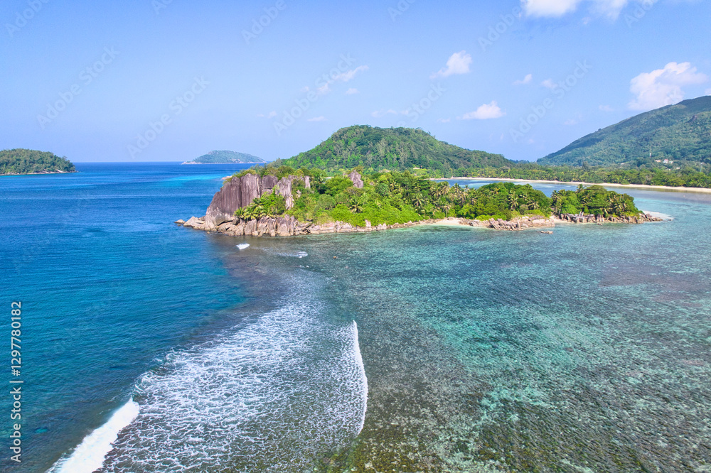 Obraz premium Drone shot of port glaud beach, island in the foreground, coral reef barrier, granite stones, white sandy beach and clear turquoise water, Mahe, Seychelles. 1