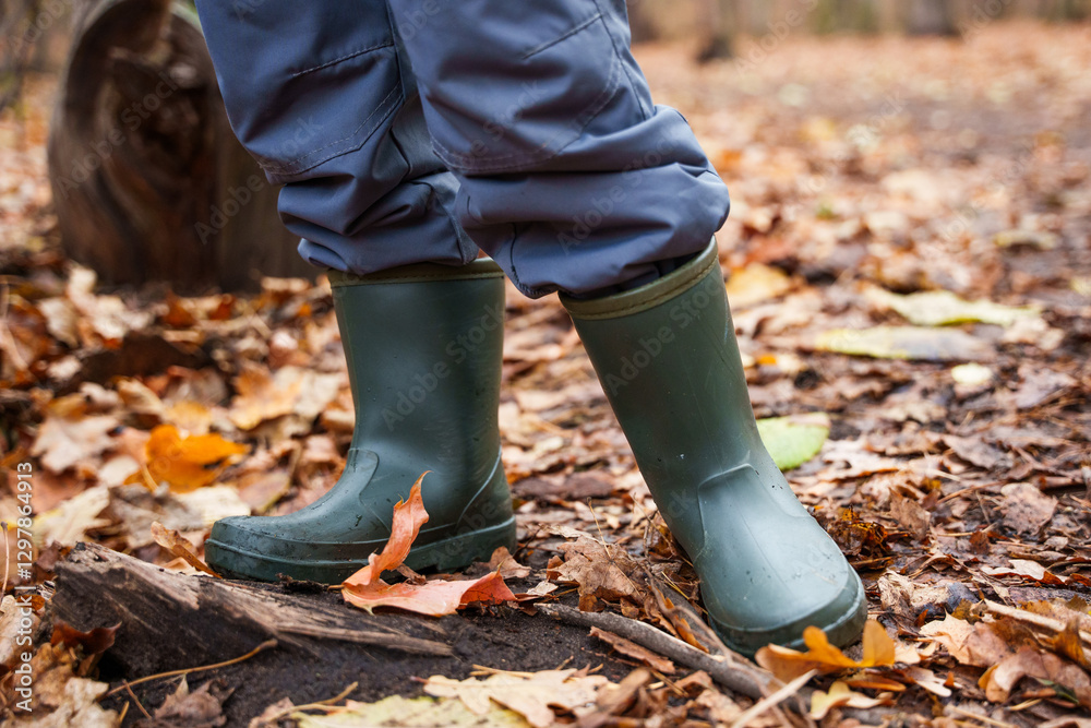dark green khaki rubber boots on a child in a dirty autumn forest leaves underfoot dark green khaki rubber boots on a child in a dirty autumn forest leaves underfoot