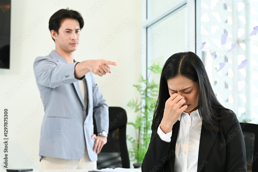 A man points at a woman who is crying in a business setting. A man points at a woman who is crying in a business setting.