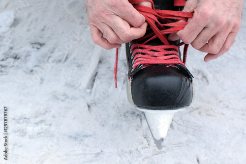 Man ties his shoelaces on hockey skates on an ice skating rink. Hockey equipment.