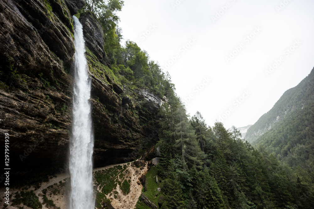 Obraz premium Pericnik waterfall is a beautiful drop from the mountain cliff, in Triglav National Park. Slovenian waterfall. Long for walking and trekking, enter inside the cave to admire it. Powerful and majesty.