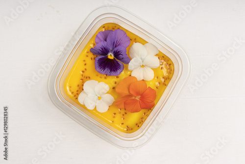 A luxurious mango dessert with a mix of purple, white, and orange edible flowers, creating a visually appealing gourmet dish. photo