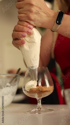 Women's hands cook tiramisu in glasses. A stylish and beautiful dessert. Delicious and mouthwatering video.