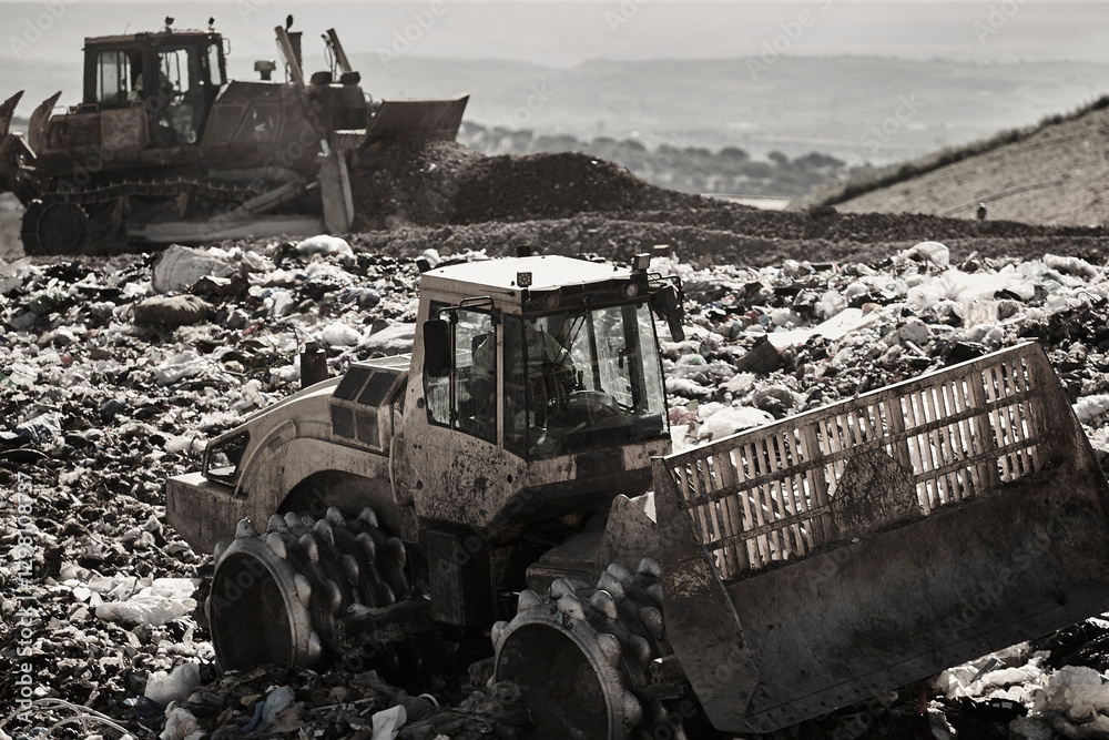 Heavy machinery shredding garbage in an open air landfill. Pollution