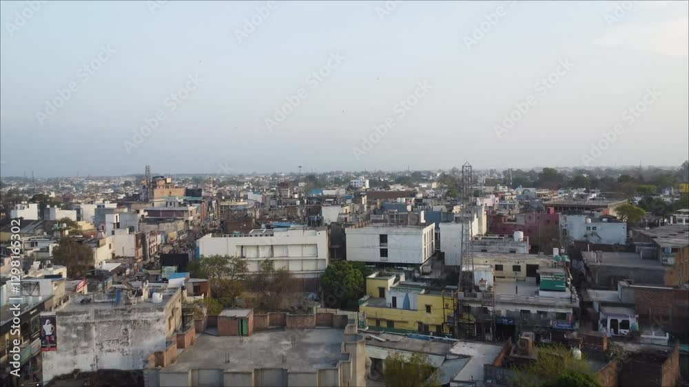 Drone flying on overpopulated city with busy streets, trees and stacked houses on a sunny day