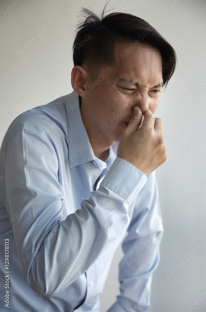 Middle aged old Asian man covering, pinching nose to prevent bad stinking smell, stinking odor, rotten smell with disgusting expression or reaction Middle aged old Asian man covering, pinching nose to prevent bad stinking smell, stinking odor, rotten smell with disgusting expression or reaction