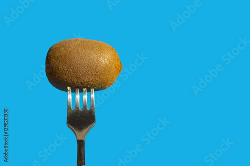 ripe kiwi on a metal fork. juicy, green fruit. background for the design. the blue color.
