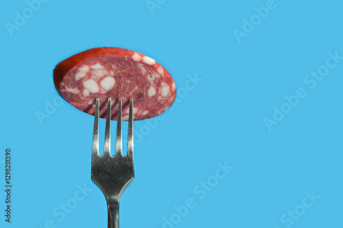 a piece of meat sausage with bacon on a metal fork. background for the design. the blue color.
