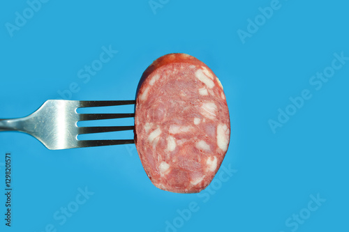 a piece of meat sausage with bacon on a metal fork. background for the design. the blue color.