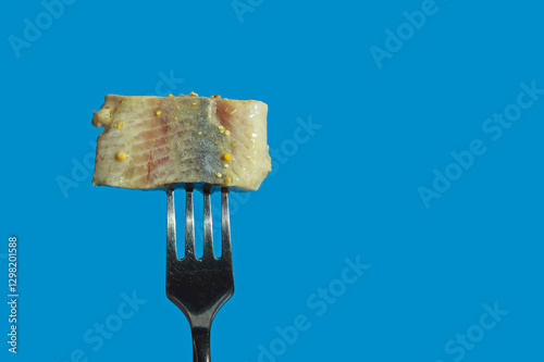 a piece of herring on a fork. healthy, salty, fatty fish in oil with spices. background for the design. the blue color.