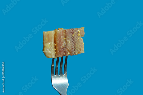 a piece of herring on a fork. healthy, salty, fatty fish in oil with spices. background for the design. the blue color.