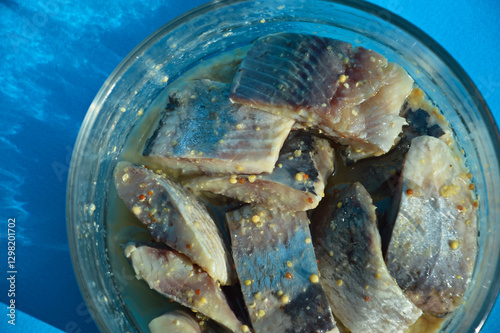 a piece of herring in a glass dish. healthy, salty, fatty fish in oil with spices. background for the design. the blue color.