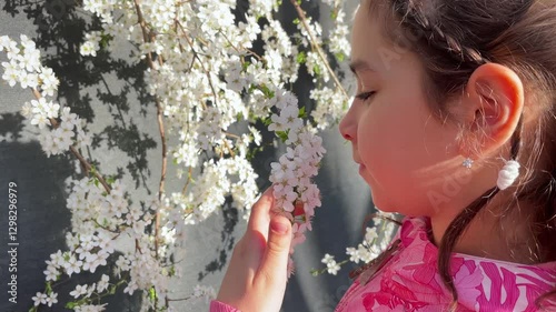 Young Girl in Pink Smelling White Spring Blossoms in Warm Sunlight