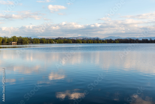 Pond with hills on the background and sky mirroring on waterground during early springtime evening photo