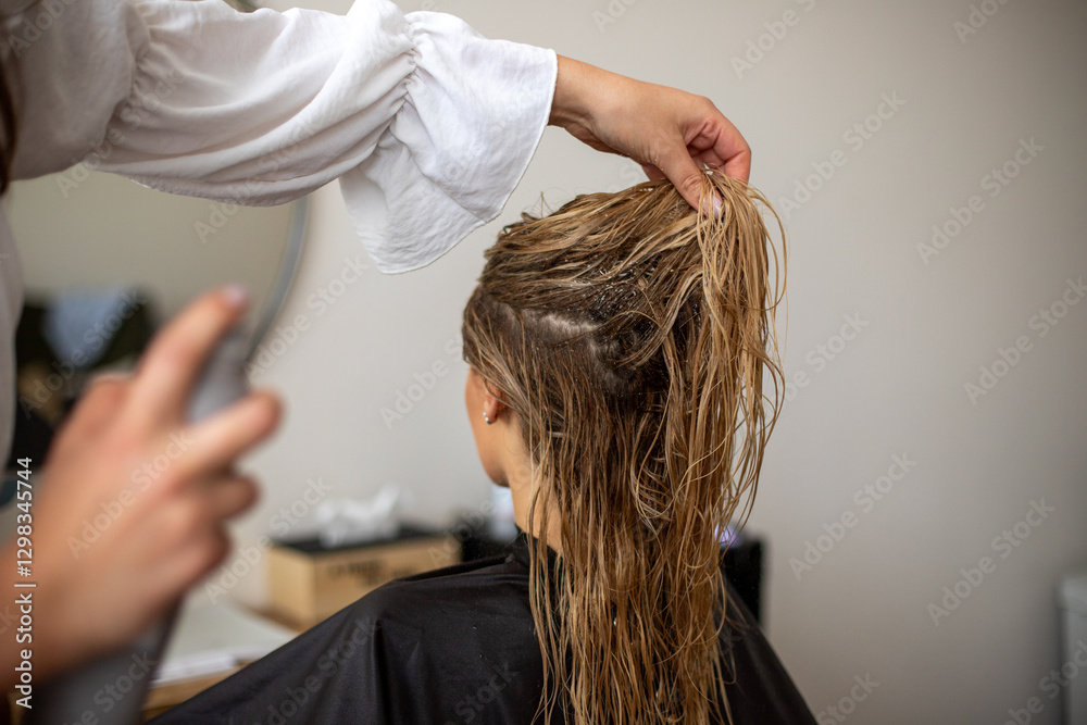 Fototapeta premium women hairdresser makes the models blonde wet hair by spraying hairspray