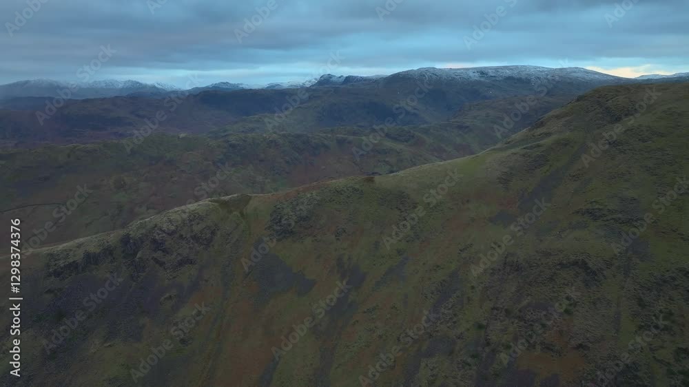 Descending drone shot next to mountain shoulder with other mountains visible in the distance. Lake District, Cumbria, UK. Descending drone shot next to mountain shoulder with other mountains visible in the distance. Lake District, Cumbria, UK.