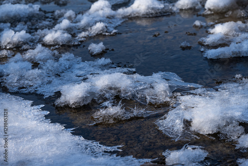 mountain river with pebbles at the bottom covered with ice with patterns