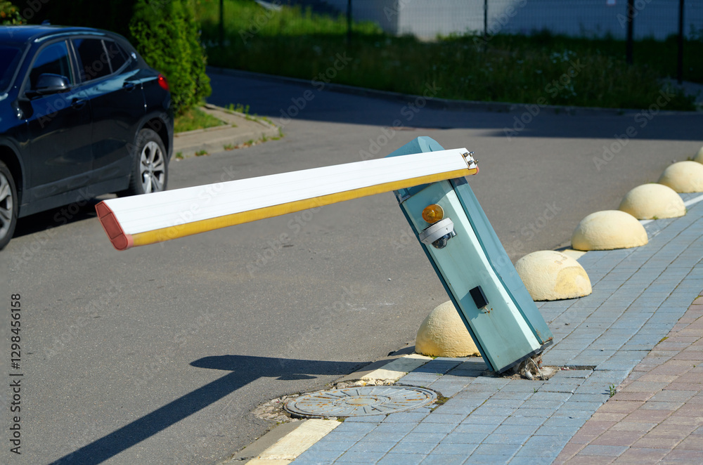Damaged automatic parking barrier, tilted barrier with torn out fastenings from the sidewalk. Broken parking barrier indicating an accident. Traffic accident.