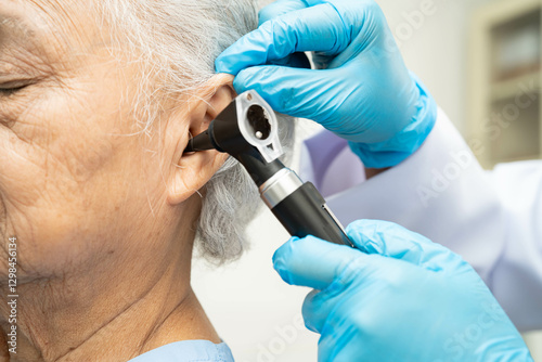 Otolaryngologist or ENT physician doctor examining senior patient ear with otoscope, hearing loss problem. photo