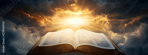 An open Bible with rays of light shining down on it, the background is dark and cloudy

