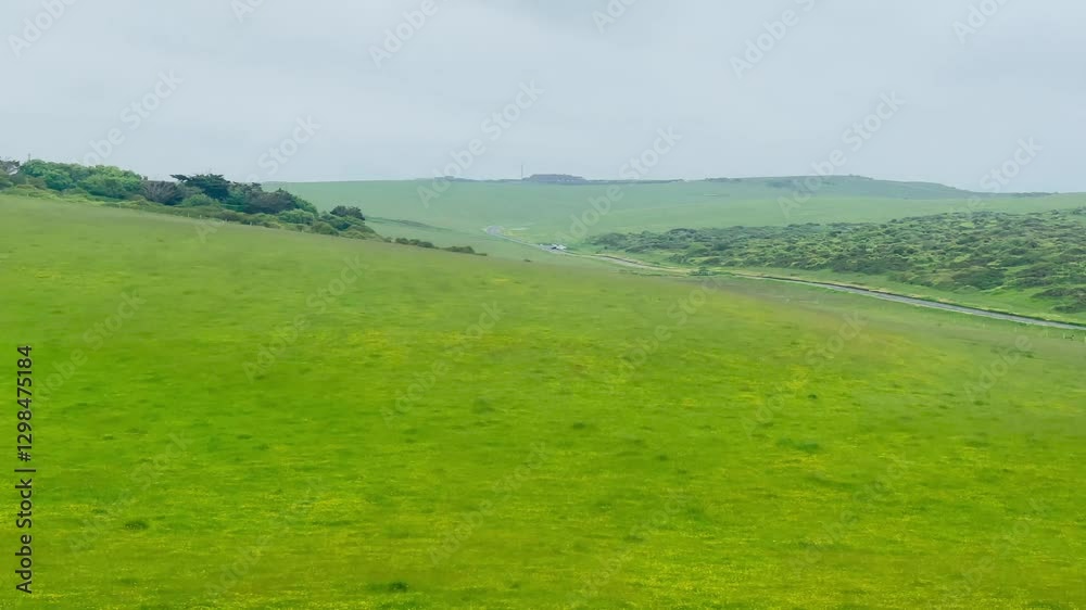 Expansive green fields stretch towards the rolling hills in Eastbourne, East Sussex, United Kingdom, evoking the timeless charm of the English countryside on a calm, overcast day Expansive green fields stretch towards the rolling hills in Eastbourne, East Sussex, United Kingdom, evoking the timeless charm of the English countryside on a calm, overcast day