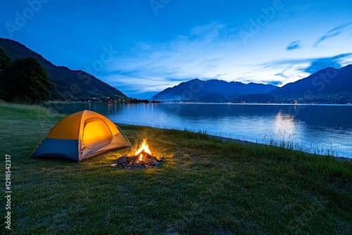 A lakeside campsite with a glowing bonfire, tents, and the lake shimmering under the night sky photo