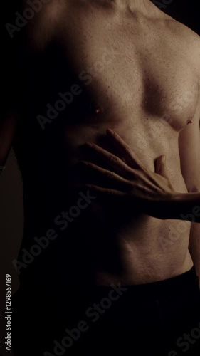 Female hands touching male's fit torso with passion. Slow motion. Vertical orientation