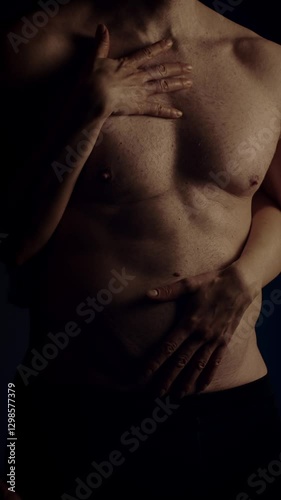 Female hands touching male's fit torso with passion. Slow motion. Vertical orientation