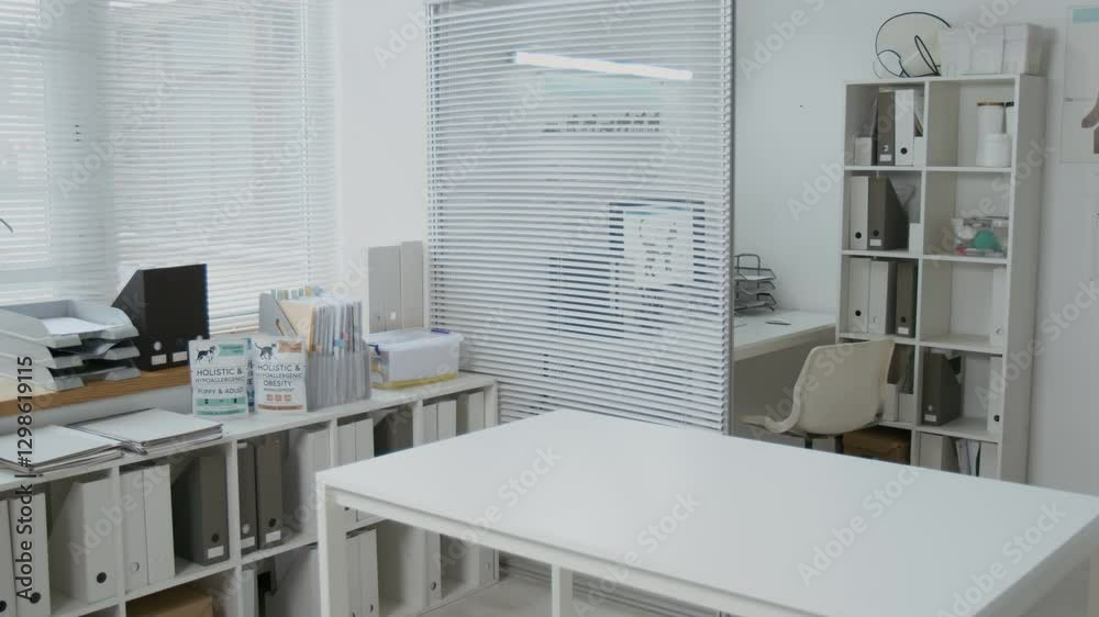 Workplace of veterinarian with medical table for examining domestic animals, shelves with folders containing paper documents and desk with computer in contemporary veterinary clinics Workplace of veterinarian with medical table for examining domestic animals, shelves with folders containing paper documents and desk with computer in contemporary veterinary clinics