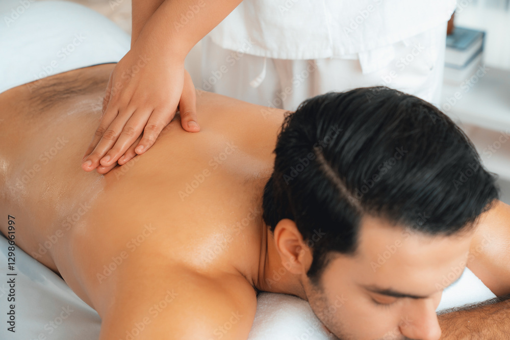 Caucasian man customer enjoying relaxing anti-stress spa massage and pampering with beauty skin recreation leisure in day light ambient salon spa at luxury resort or hotel. Quiescent Caucasian man customer enjoying relaxing anti-stress spa massage and pampering with beauty skin recreation leisure in day light ambient salon spa at luxury resort or hotel. Quiescent