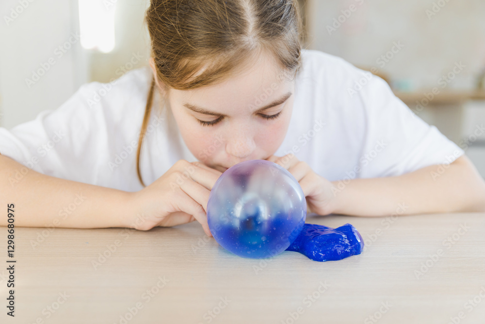 A joyful girl blows a colorful slime bubble, her smile radiating happiness. This playful moment captures the essence of childhood creativity and fun A joyful girl blows a colorful slime bubble, her smile radiating happiness. This playful moment captures the essence of childhood creativity and fun