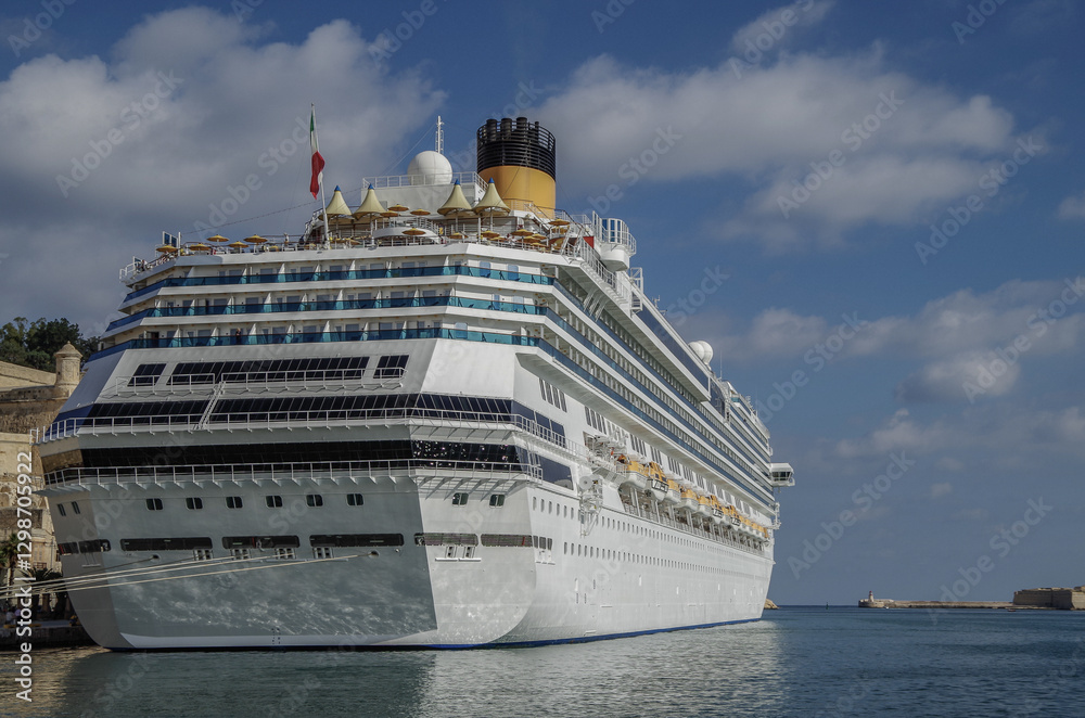 Gigantic cruiseship cruise ship liner Fascinosa docked at pier terminal in old town Valletta, Malta with historic buildings, city skyline and harbor entrance Gigantic cruiseship cruise ship liner Fascinosa docked at pier terminal in old town Valletta, Malta with historic buildings, city skyline and harbor entrance