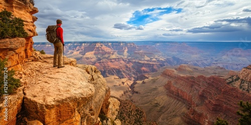 Hiker overlooking majestic Grand Canyon landscape at sunset with dramatic clouds and vibrant rock formations