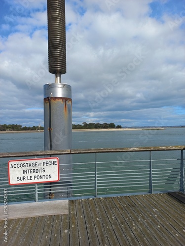 Panneau ccostage et peche interdits sur le ponton en bord de mer ave une ile en arrière-plan photo