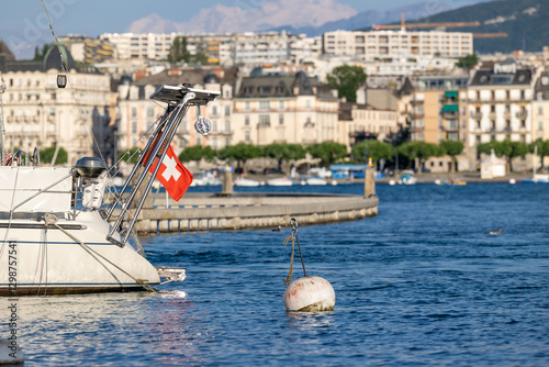Yacht on Lake Geneva with Swiss flag. Blue water at the dock of boats