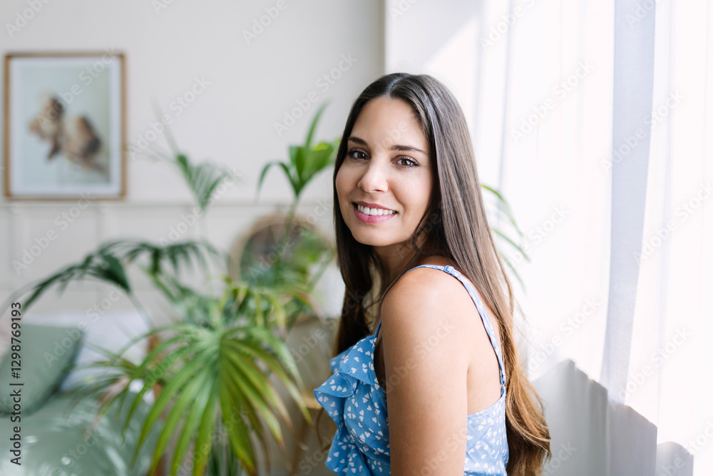 Young woman with long brown hair smiling near a window in a bright, modern apartment filled with houseplants, enjoying the natural light Young woman with long brown hair smiling near a window in a bright, modern apartment filled with houseplants, enjoying the natural light