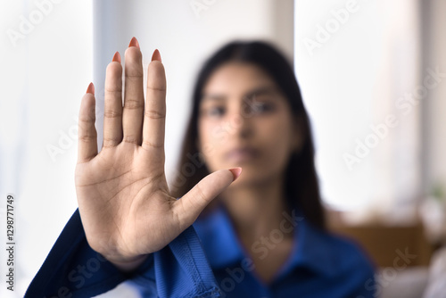 Woman holds up her hand in stop gesture, as symbol of resistance, defiance, or protest, struggling social issues, against racial discrimination, sexism, harassment, and gender-based violence, close up photo