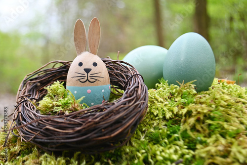 Osternest mit Holzhäschen und bunt gefärbten Eiern im Wald