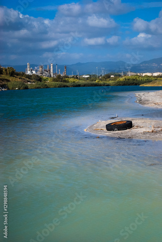 Un vecchio pneumatico abbandonato sulla spiaggia di Rosignano Solvay in Toscana con sullo sfondo lo stabilimento per la produzione del bicarbonato photo