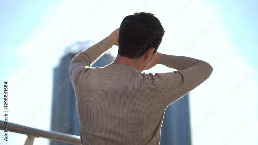 A person is standing outdoors, delighting in the warm sunlight while admiring a vibrant urban skyline backdrop A person is standing outdoors, delighting in the warm sunlight while admiring a vibrant urban skyline backdrop